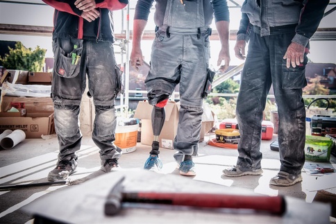 Drei Bauarbeiter auf einer Baustelle - Ein Bauarbeiter mit Prothese